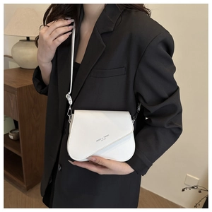 Detail of white leather saddle bag with asymmetric flap and FASHI de TREND lettering