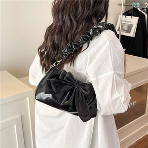 Chic black glossy shoulder bag with large bow and ruched strap for fashionable women