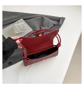 Detail of red crocodile texture handbag with gold magnetic closure and knot handle