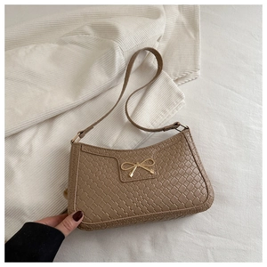 Détails de la texture crocodile kaki et du nœud en métal doré sur le sac à main chic