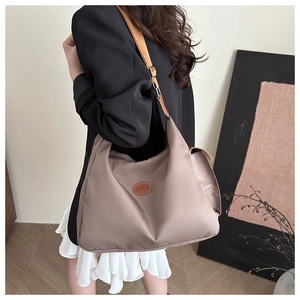 Detail of light brown nylon hobo bag with a leather fashion patch and adjustable strap