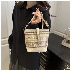Close-up of woven bucket bag featuring gold twist-lock and white faux leather trim