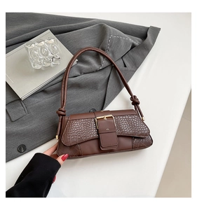 Detail of dark brown baguette bag with crocodile texture, leather拼接 and gold buckle