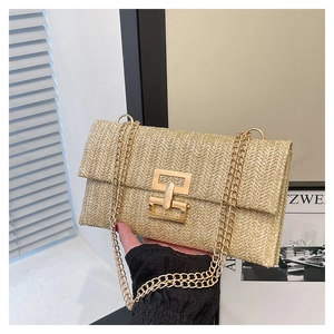 Close-up of woven straw texture with gold interlocking lock and metal chain strap