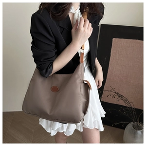 Detail of adjustable brown leather strap and gold buckle on coffee nylon crossbody bag