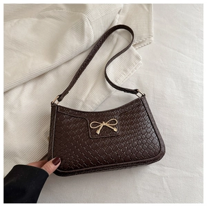 Détail d'un sac d'épaule marron à texture tressée avec fermoir nœud en métal doré