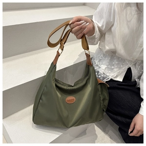 Detail of olive green nylon tote with leather trim and fashion patch on stairs