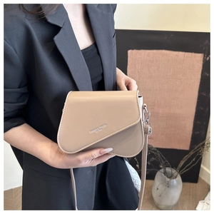 Detail of beige leather crossbody bag with asymmetric flap and fashion trend engraving