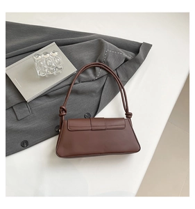 Close-up of a dark brown crocodile texture baguette bag with stylish knotted shoulder strap