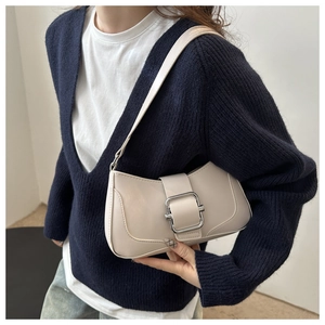 Close-up of off-white baguette bag with large metal buckle on a shoulder strap