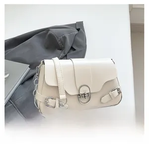 Détail du sac en cuir crème avec bandoulière chaîne argentée et fermoir en métal rond