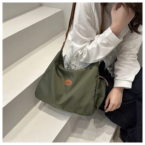 Close-up of olive green nylon tote bag featuring a brown leather fashion patch and strap