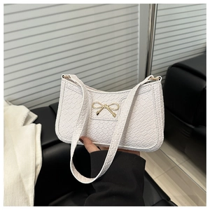 Détail du sac bandoulière blanc tressé avec fermoir papillon doré en vue rapprochée