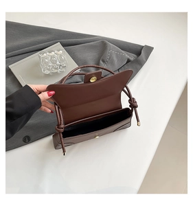 Detail view of the brown leather shoulder bag featuring magnetic closure and dark lining
