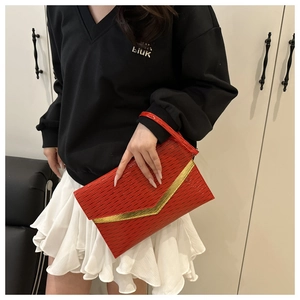 Detailed shot of red envelope clutch with woven texture and gold V-shaped metal trim