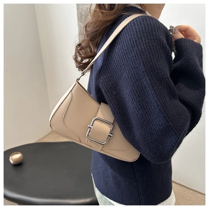 Detail of beige shoulder bag featuring a large silver square metal buckle and smooth faux leather