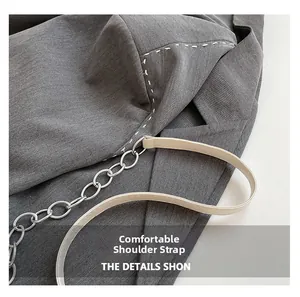 Détail de la chaîne en métal et de la bandoulière en cuir crème avec blazer gris