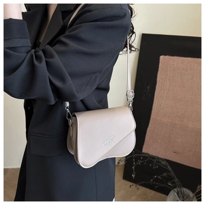 Detail of minimalist beige saddle bag flap with 'FASHION TREND' text on black blazer