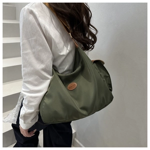 Detailed side view of an olive green nylon hobo bag with brown leather shoulder strap