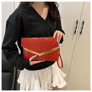 Detail of red envelope clutch with V-shaped gold metal trim and ripple texture
