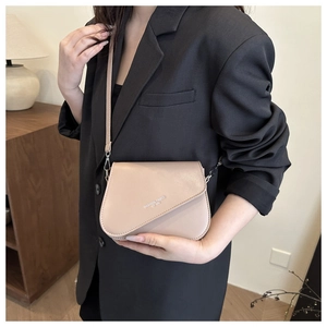Detailed view of beige square crossbody bag with fashion trend lettering on black blazer