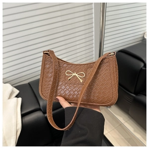 Détail d'un sac à main marron café à texture tressée avec un nœud métallique doré