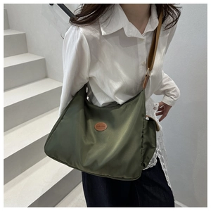 Olive green crossbody bag with adjustable brown strap and fashion label detail on stairs