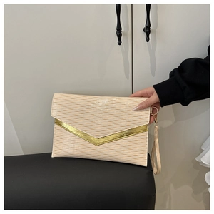 Close-up of cream envelope clutch featuring wavy texture and golden V-shaped metal trim