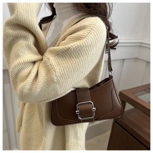 Detail of a brown shoulder bag featuring a large silver square buckle and leather texture
