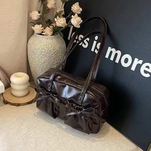 Détail d'un sac cabas marron foncé en cuir verni avec de grands nœuds élégants décoratifs