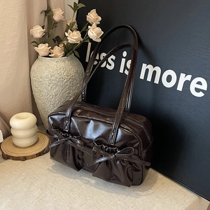 Détail du sac cabas en cuir verni marron foncé avec poches à nœuds et fini brillant