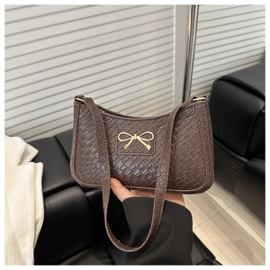 Détail du sac baguette marron foncé avec texture crocodile et nœud doré élégant