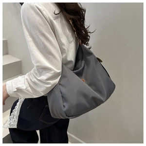 Detail of grey nylon hobo bag with contrast brown leather strap and side round patch logo