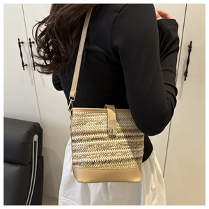 Detailed view of woven straw bucket bag with faux leather straps and metal clasp closure