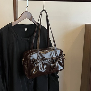 Détail du sac fourre-tout en cuir brillant chocolat avec des nœuds sur les poches avant