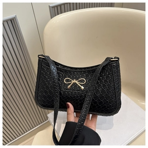 Détail du sac à bandoulière tressé noir avec fermoir nœud doré et bandoulière fine