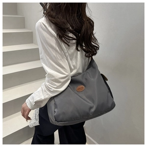 Close-up of gray nylon shoulder bag featuring a leather fashion patch and durable texture