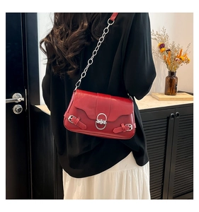 Détail du sac sous le bras en cuir rouge avec boucle argentée et bandoulière en chaîne