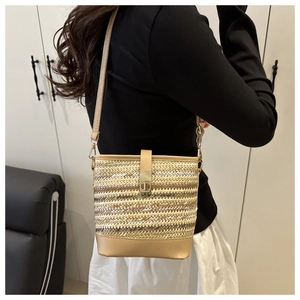Close-up of woven straw and gold leather bucket bag with metal turn-lock buckle