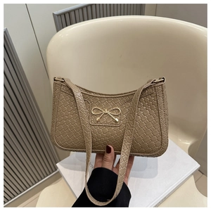 Détail du sac sous le bras beige à texture tressée avec une boucle en métal doré en nœud