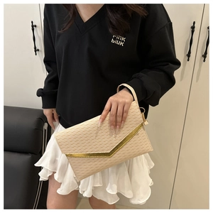 Detailed view of cream envelope clutch with wavy texture and golden V-shaped metal trim
