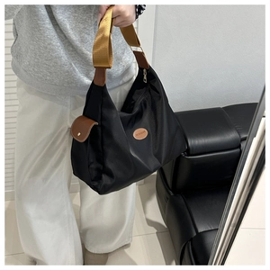 Close-up of black nylon tote bag with fashion patch and snap button side pocket