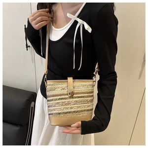 Detail of woven straw bucket bag with khaki stripes and elegant leather strap finish
