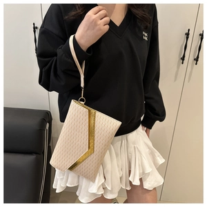 Detail of cream envelope clutch with wavy texture and gold V-shaped metal buckle