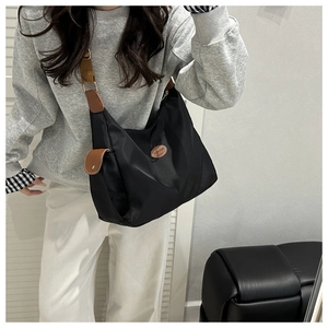 Close-up of stylish black crossbody bag with brown leather accents and FASHION label