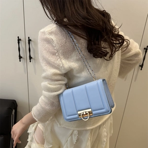 Sac bandoulière matelassé bleu clair avec chaîne et fermoir doré sur modèle