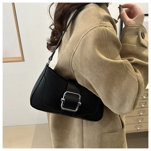 Side view of a minimalist black matte underarm bag with a silver square buckle on a model