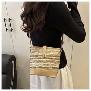 Detail of woven bucket bag featuring straw texture and faux leather strap with gold buckle