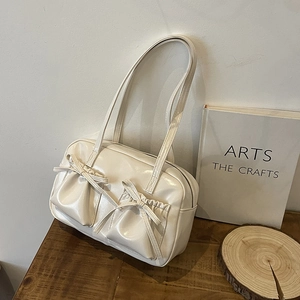 Détail du sac bowling crème avec poches à nœuds et finition en cuir synthétique verni