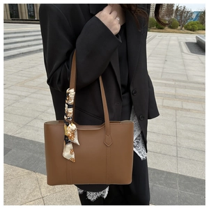 Brown PU leather tote bag with a patterned silk scarf handle detail worn by a model
